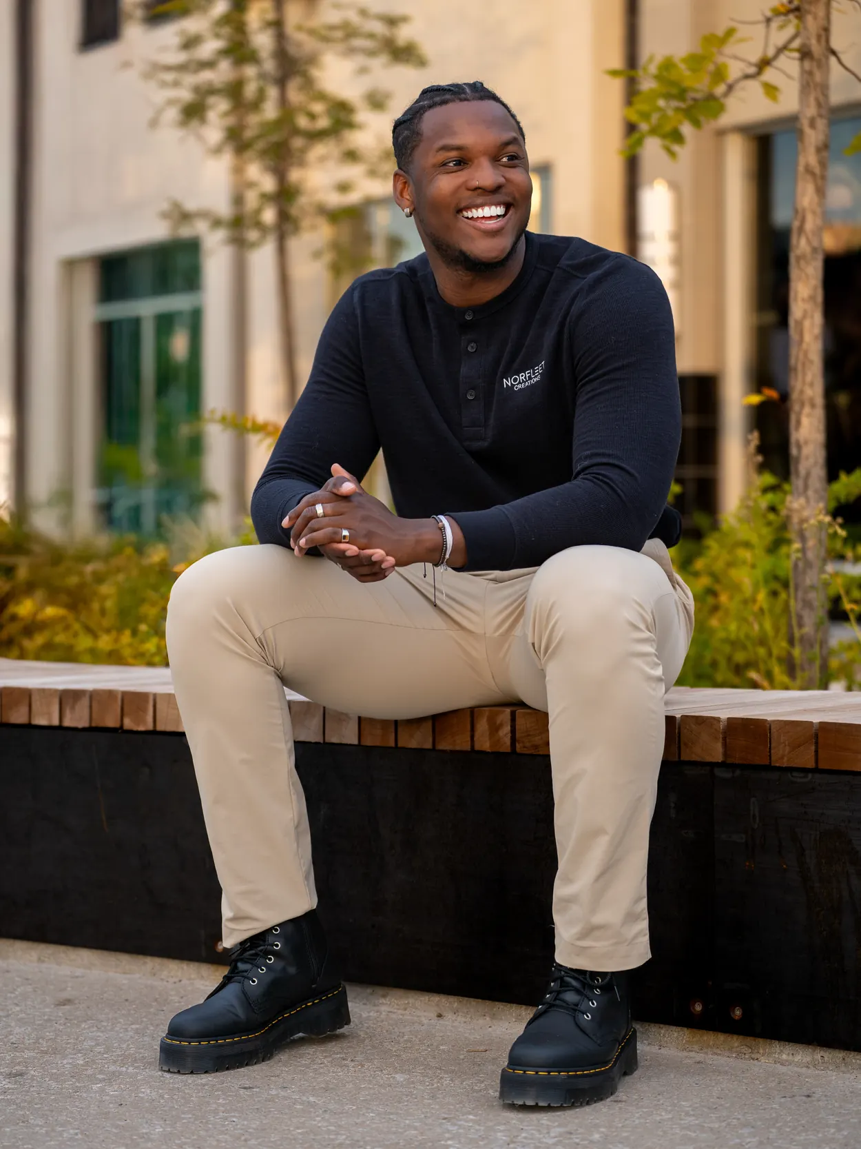 Isaiah Norfleet, smiling, seated outdoors in a Norfleet Créations shirt
